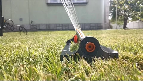 Close up of an oscillating lawn sprinkler spraying water on fresh green grass Video stock 339171848