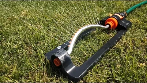 Close up of an oscillating lawn sprinkler spraying water on fresh green grass Video stock 339171907