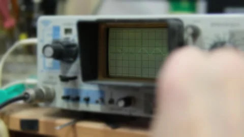 Close-up of an Oscilloscope Screen Displaying a Green Waveform Signal with Stock-Footage 301184574