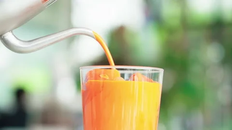 Close up ouring thai tea from pot to glass with orange ice inside in white Video stock 156248232