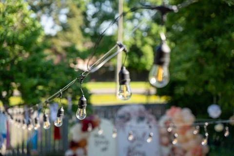 Close up of outdoor string lights with blurred garden background Stock Photos