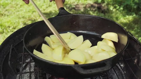 Close-up of outside on the grill coals, potatoes cut into slices are being fried Stock Footage 317933087