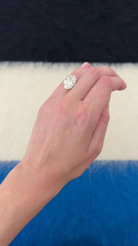 Close up oval diamond engagement ring against blue and white surface Stock Footage 328251116