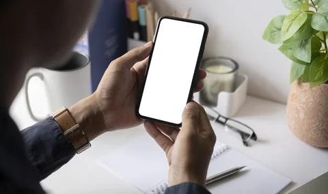 Close up over shoulder businessman using mobile phone at office desk. Stock Photos