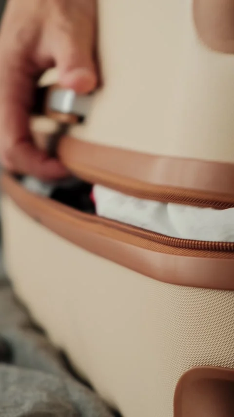 Close up of overflowing suitcase. Hands pushing clothes into overloaded luggage Stock-Footage 346244539
