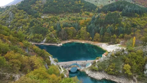 Close overhead drone view of red pedestrian bridge crossing turquoise 스톡 동영상 330990133