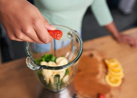 Close up overhead shot of hands preparing smoothie in glass blender strawberry Stock Photos
