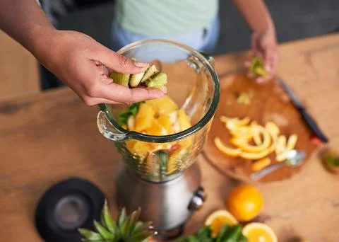 Close up overhead shot of hands preparing smoothie in glass blender kiwi Stock Photos