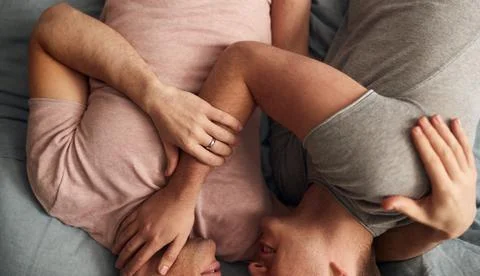 Close Up Overhead Shot Of Loving Same Sex Male Couple Lying On Bed At Home Stock Photos