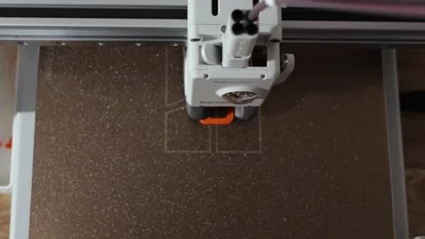 Close-up overhead view of a 3D printer creating a white outline on a textured Видео 339203478