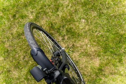 A close-up overhead view of a bicycle's front wheel resting on a green gras.. 스톡 사진