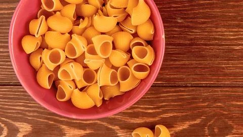 Close up overhead view of dry shell pasta in a pink bowl Stock Photos
