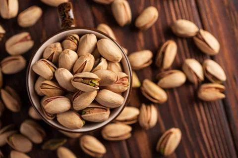 Close-up overhead view of shelled and unshelled pistachios in a rustic bowl.. Stock Photos
