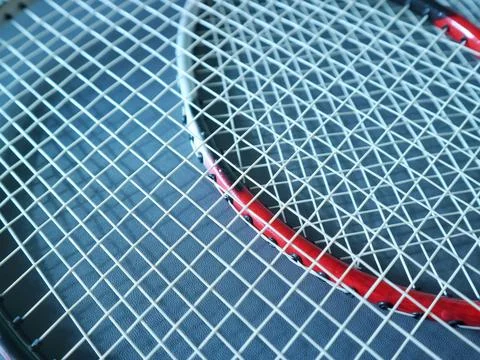 Close-up of overlapping worn racket strings and red frame Stock Photos