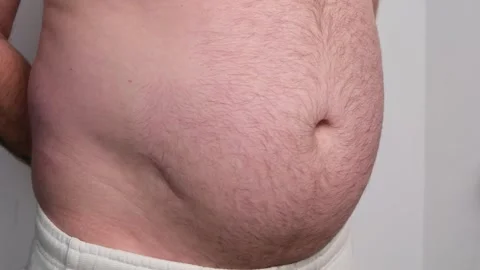 Close-up of an overweight man's torso on a white background, slapping his hairy 스톡 동영상 337723346