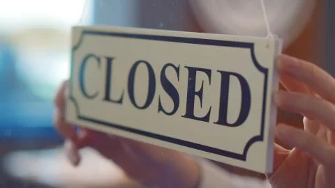 Close up of owner turning closed sign at bar or restaurant glass door or window Stock Photos