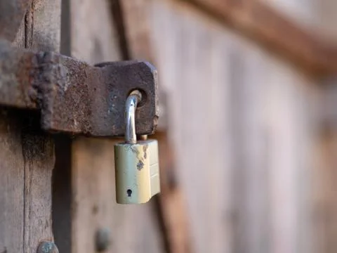 Close up of a padlock securing a rusty and weathered wooden door Stock Photos
