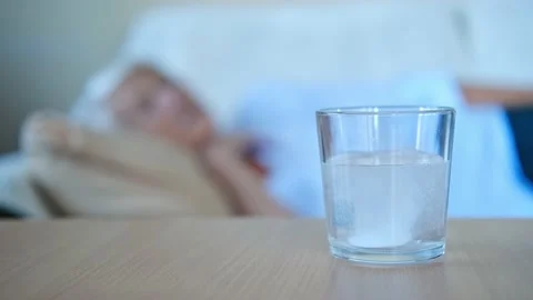 Close up painkiller tablet dissolves in glass on table in the background with Stock Footage 158053504
