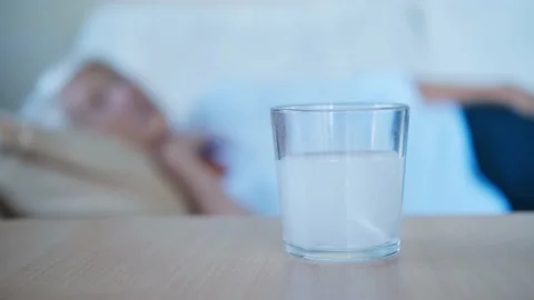 Close up painkiller tablet dissolves in glass on table in the background with Stock Footage 159368004