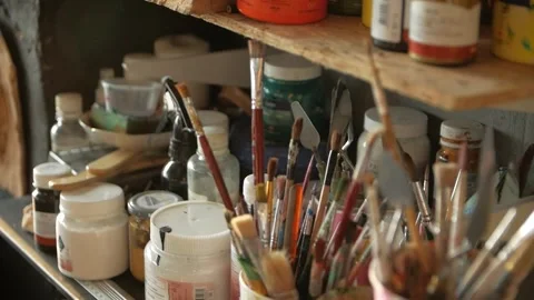 Close-up of paint brushes in plastic cups and paints lying on the shelves. Stock Footage 272223970