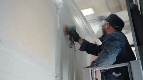 Close-up of a paint line worker in a respirator sanding the car wall before Stock Footage 196357109