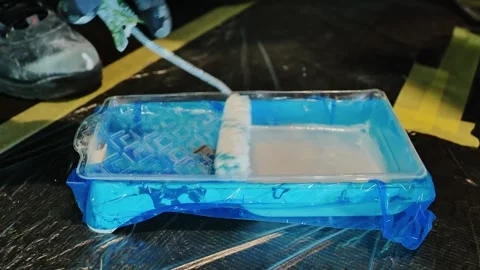 Close-up of paint roller dipped into primer tray on construction floor Stock Footage 321721128