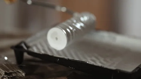 Close-up of Paint Roller Dipped into White Paint in Tray, Preparing for Wall or  Stock Footage 332923653