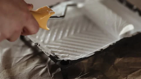 Close-up of Paint Roller Dipped into White Paint in Tray, Preparing for Wall or  Stock Footage 332923968