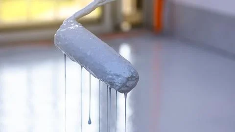 Close-up of a paint roller, gray paint flows down the roller Stock Photos