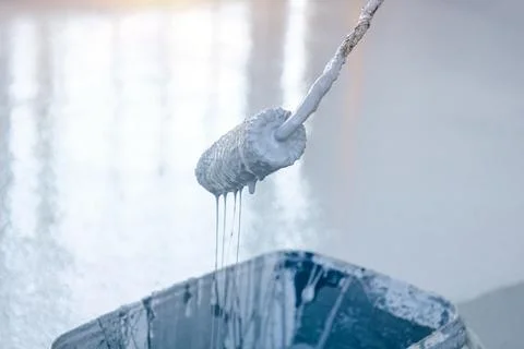 Close-up of a paint roller, gray paint flows down the roller Stock Photos