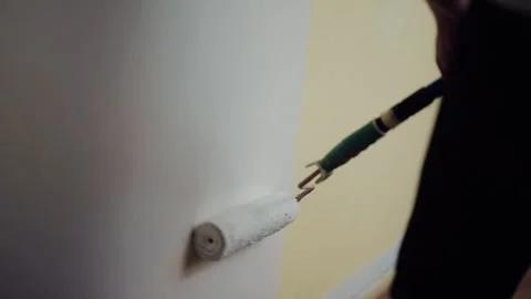 Close up of paint roller tool covering dark wall with white paint, home Stock Footage 345138084
