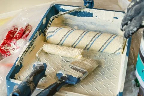 Close up of paint rollers and brushes in tray on plastic drop cloth Stock Photos