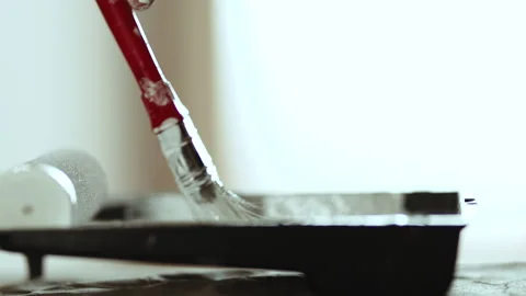 Close-up of Paintbrush Dipped into White Paint in Plastic Tray, Preparation for  Stock Footage 332924952