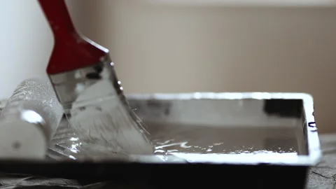 Close-up of Paintbrush Dipped into White Paint in Plastic Tray, Preparation for  Stock Footage 332924957
