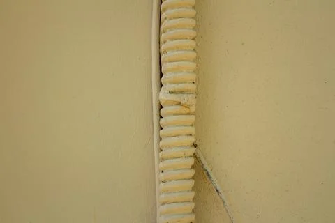 Close-up of a painted cable conduit attached to a yellow textured wall Stock Photos