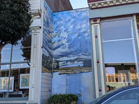 Close-up of painted mural between two windows showing tranquil sky 库存照片