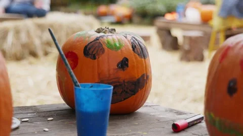 Close-Up of a Painted Pumpkin with Spooky Face and Paint Supplies Stock Footage 319470383