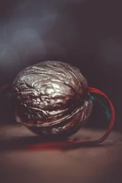 Close-up of a painted silver nut with red and green ribbon on a dark backgrou Stock Photos
