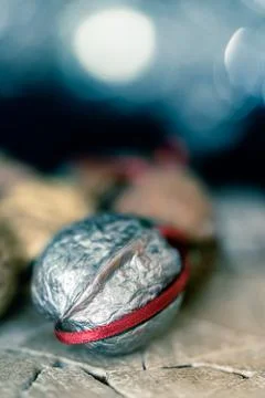 Close-up of a painted silver nut with red and green ribbon on a dark backgrou Stock Photos
