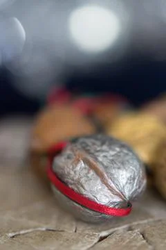 Close-up of a painted silver nut with red and green ribbon on a dark backgrou Stock Photos