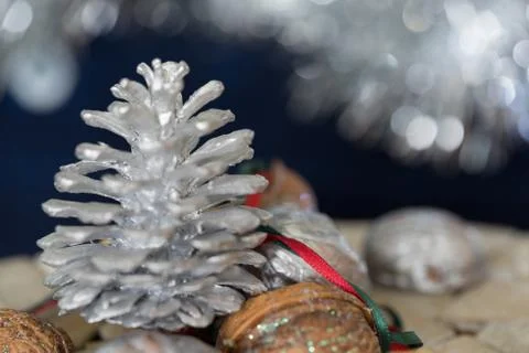 Close-up of a painted silver pine cone with red and green ribbon on a dark ba Stock Photos