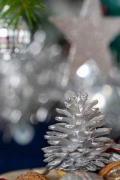 Close-up of a painted silver pine cone with red and green ribbon on a dark ba Stock Photos