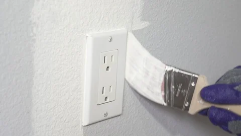 Close up of painter hands with gloves painting the wall around power outlet. Stock Footage 129140273