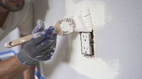 Close up of painter hands with gloves painting the wall around power outlet. Stock Footage 129140321