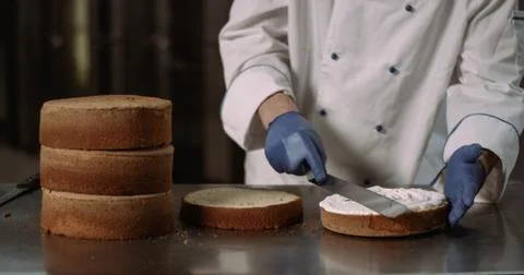 A close up of a pair of blue gloves holding a spatula and gracefully spreading Stock Photos