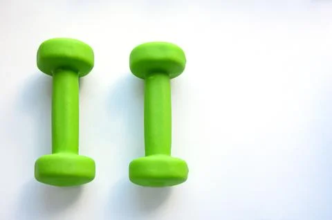 Close-up of a pair of bright green small female dumbbells on a white plastic Stock Photos