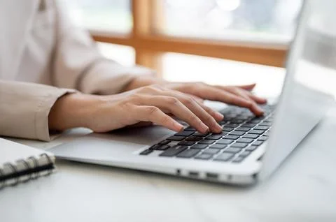 Close up pair of hands typing both hands on laptop keyboard at white table .. Stock Photos