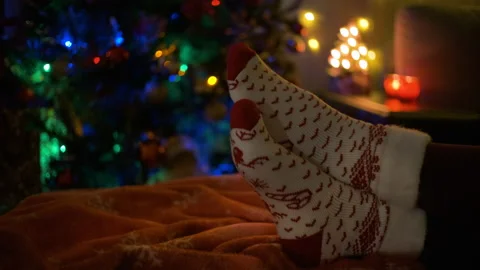 Close-up of a pair of legs in christmas socks next to a Christmas tree. Stock Footage 145026737