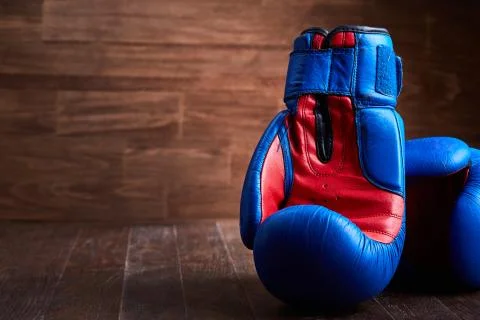 Close-up of the pair of red and blue boxing gloves on the wooden plank. Stock Photos