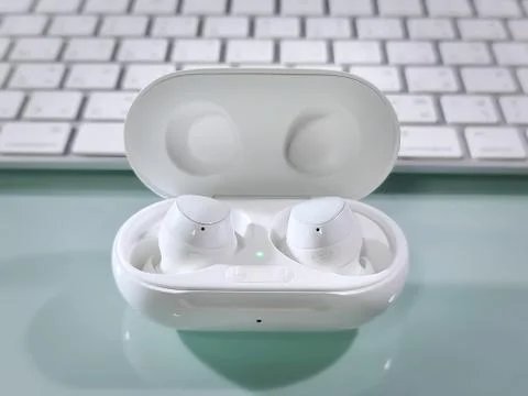 Close-up Pair of White Wireless Ear Buds in Dock on Table Foto stock